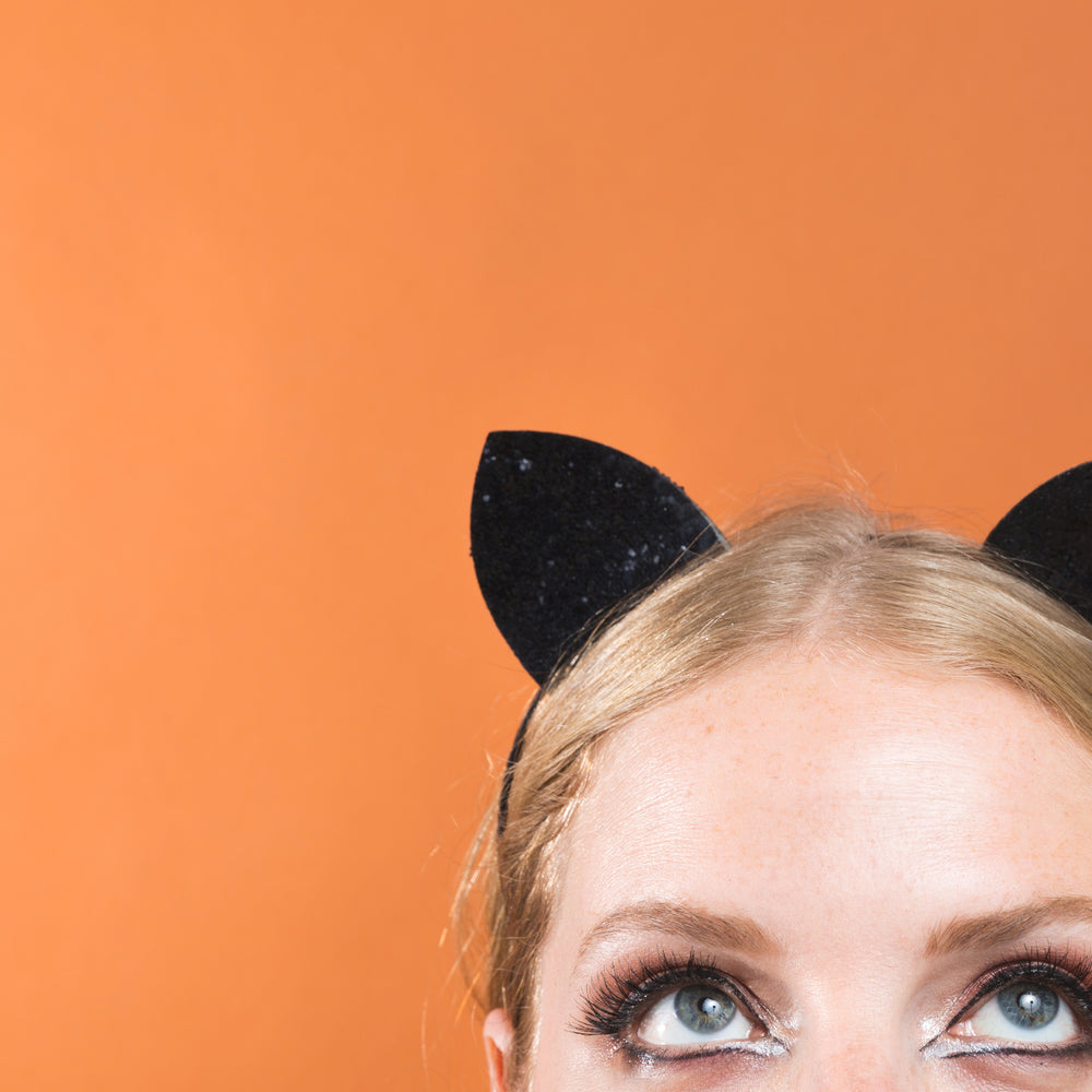 blonde woman wearing kitty cat ears, looking up.